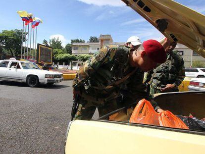 Militares venezuelanos revistam o conteúdo de um carro.