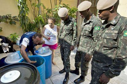 Solados e agente procuram larvas de Aedes aegypti