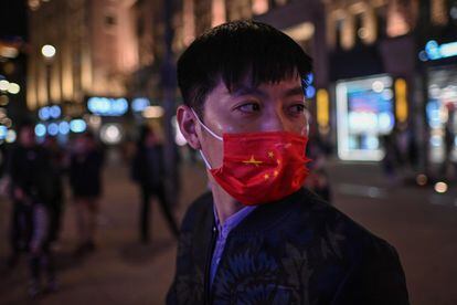 Um homem se protege com uma máscara com as cores da bandeira chinesa numa rua de Xangai.
