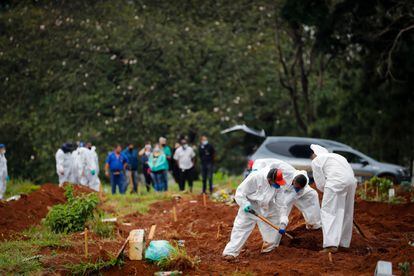 Trabalhadores enterram uma vítima de covid-19 nesta quinta-feira no Cemitério Viola Formosa, em São Paulo (Brasil).