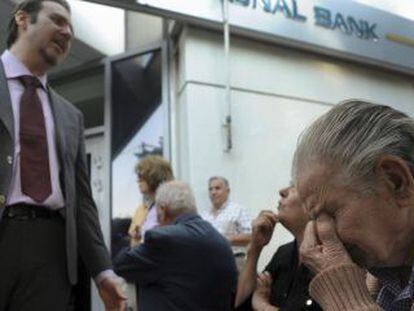 Um gerente do Banco Nacional da Grécia em Tessalônica explica a situação a um grupo de pensionistas que espera do lado de fora da agência.