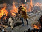 A man runs past the burning funeral pyres of those who died from the coronavirus disease (COVID-19), during a mass cremation, at a crematorium in New Delhi, India April 26, 2021. REUTERS/Adnan Abidi     TPX IMAGES OF THE DAY
