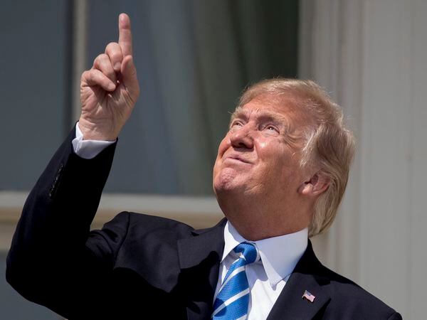 FILE - In this Aug. 21, 2017, file photo, President Donald Trump points to the sun as he arrives to view the solar eclipse at the White House in Washington. Trump's comment about injecting disinfectant to fight coronavirus is just the latest in a long list of comments and actions that run contrary to mainstream science. He's gone against scientific and medical advice by staring at an eclipse without protection, calling climate change a hoax and saying wind turbines cause cancer.  (AP Photo/Andrew Harnik, File)