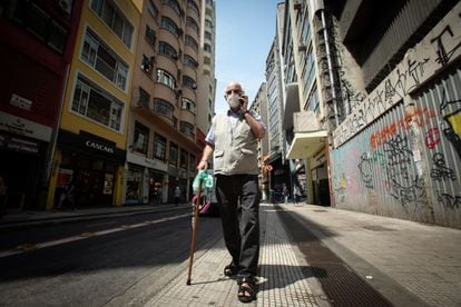 O padre Julio Lancellotti caminha pelas ruas do centro de São Paulo enquanto fala no telefone celular.