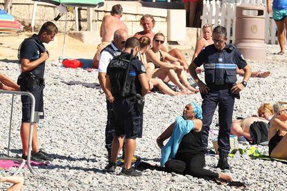 Uma mulher tira a camisa, enquanto a polícia aplica uma multa em Nice.