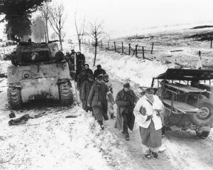Presos alemães passam por um Sherman e um jeep Willys durante a batalha das Ardenas.