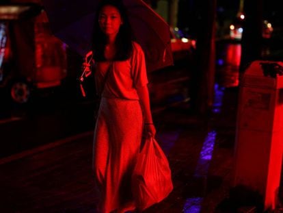 Una mujer camina en una calle iluminada con neón en el antiguo distrito de la ciudad de Liwan en Guanghzou,