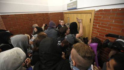 Vários encapuzados esmurram a porta onde deveria acontecer uma cerimônia na Universidade Autônoma.