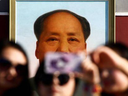 Três mulheres tiram uma foto na frente do retrato de Mao Tse-Tung na praça de Tiananmen em Pequim.