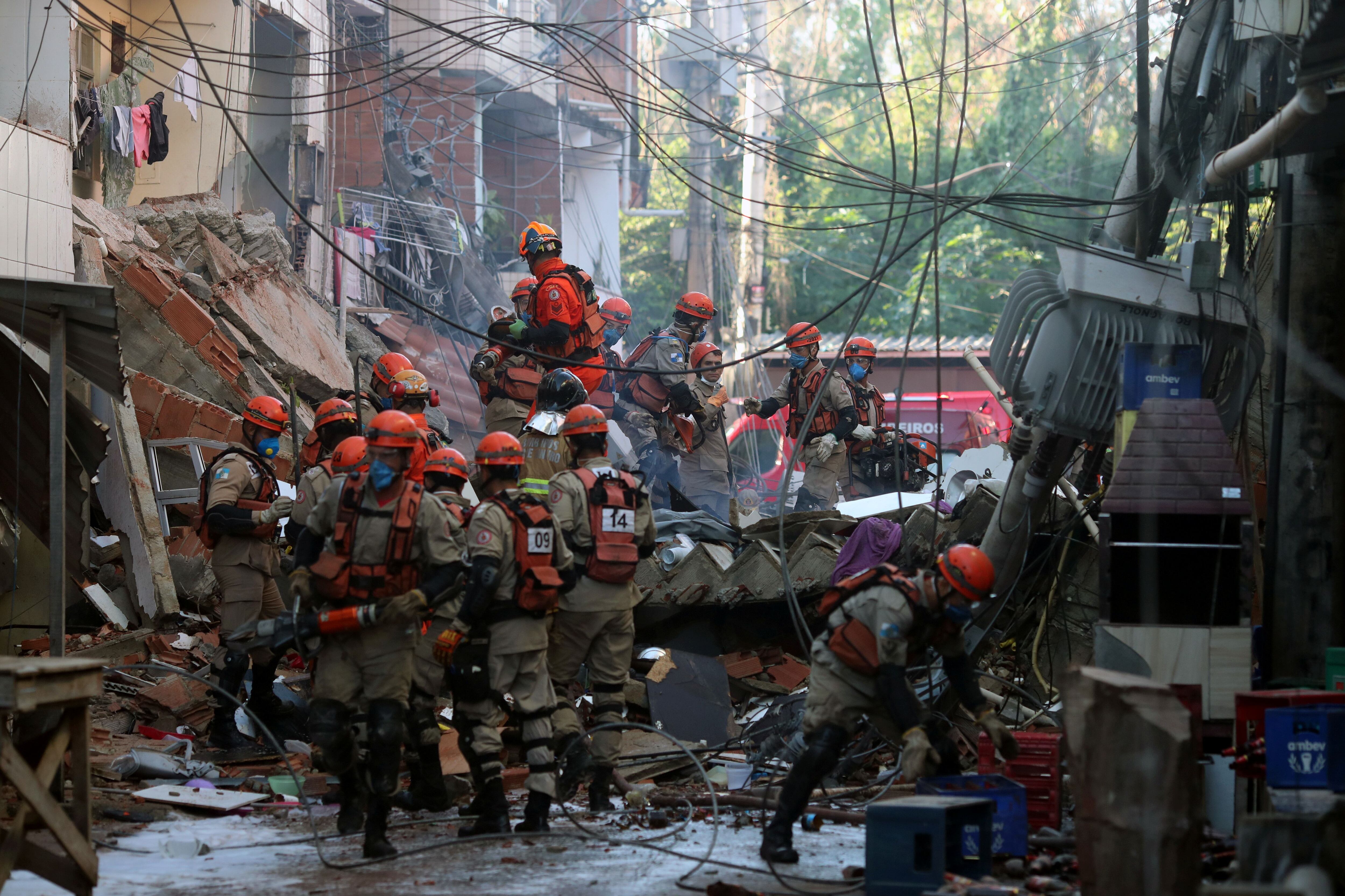 Bombeiros tentam resgatar outras pessoas presas aos escombros após desabamento de prédio de quatro andares no Rio.
