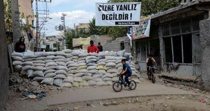 Crianças passam por uma das barricadas erguidas na localidade de Cizre por jovens curdos simpatizantes do PKK.