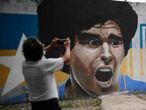 A man takes a photograph of a mural emblazoned with an image of Diego Maradona in Buenos Aires, Argentina, Wednesday, Nov. 25, 2020. The Argentine soccer great who was among the best players ever and who led his country to the 1986 World Cup title before later struggling with cocaine use and obesity, died from a heart attack on Wednesday at his home in Buenos Aires. He was 60. (AP Photo/Natacha Pisarenko)
