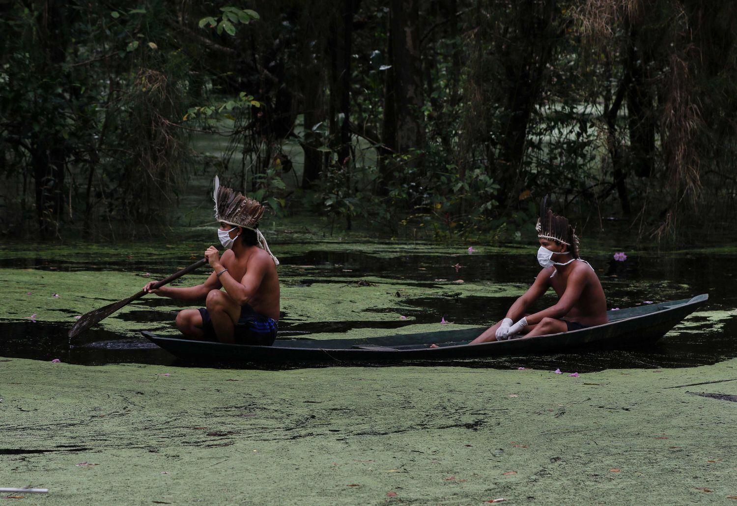 Indígenas com máscaras navegam pelo rio Ariaú, a 80 quilômetros de Manaus.