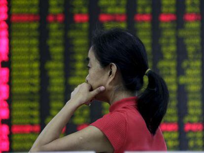 Investidora diante de um painel com os valores em Pequim.