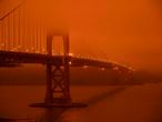 TOPSHOT - Cars drive along the San Francisco Bay Bridge under an orange smoke filled sky at midday in San Francisco, California on September 9, 2020. - More than 300,000 acres are burning across the northwestern state including 35 major wildfires, with at least five towns "substantially destroyed" and mass evacuations taking place. (Photo by Harold POSTIC / AFP)