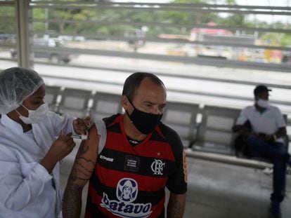 Um homem recebe uma dose da vacina da Pfizer contra a covid-19 numa estação de ônibus do Rio de Janeiro.
