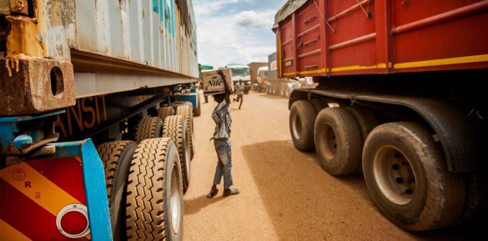 Menino ganha a vida vendendo água mineral aos caminhoneiros que esperam na fila. Martin Kharumwa.