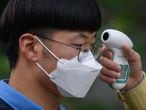 Students wearing facemasks amid concerns over the COVID-19 novel coronavirus undergo a temperature check as they arrive at Keongbok High School in Seoul on May 20, 2020. - Hundreds of thousands of South Korean students returned to classes as schools started reopening after more than a two-month delay over the coronavirus outbreak. (Photo by Ed JONES / AFP)