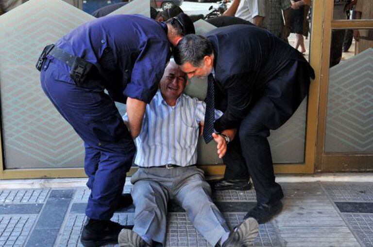 Aposentado se desespera diante de fila em agência bancária em Atenas.