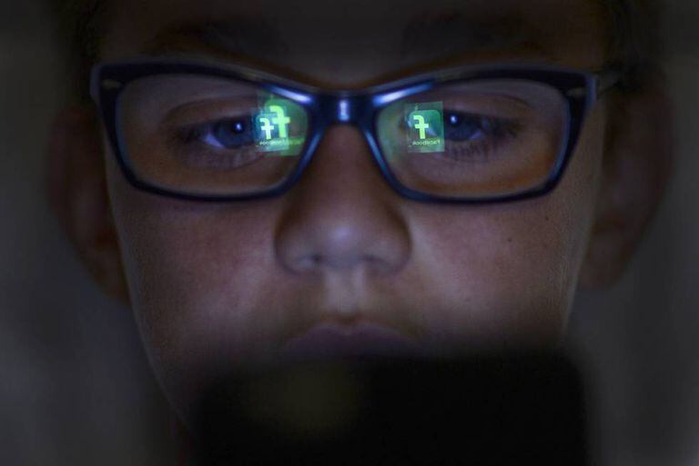 Criança com o reflexo de um smartphone no rosto
