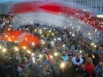 Belarusian opposition supporters light phones lights and wave an old Belarusian national flags during a protest rally in front of the government building at Independent Square in Minsk, Belarus, Wednesday, Aug. 19, 2020. The authoritarian leader of Belarus complained that encouragement from abroad has fueled daily protests demanding his resignation as European Union leaders held an emergency summit Wednesday on the country's contested presidential election and fierce crackdown on demonstrators. (AP Photo/Dmitri Lovetsky)