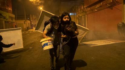 Dois jovens manifestantes procuram abrigo depois que a polícia os dispersou com gás lacrimogêneo em 14 de novembro.