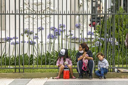 Mulher com seus dois filhos pede ajuda em uma rua de Buenos Aires, no dia 4 de dezembro.