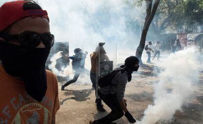 Manifestantes jogam de volta bombas de gás lacrimogêneo à polícia durante um protesto contra o Governo, na quarta-feira em Caracas.