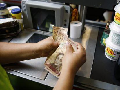 Operadora de caixa conta dinheiro em um supermercado de Caracas.