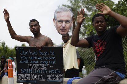 Manifestantes mostram um cartaz com o rosto do governador do Missouri, Jay Nixon.