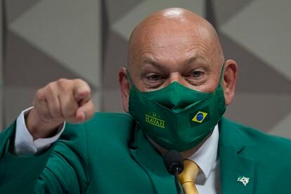 Department store magnate Luciano Hang, wearing Brazil's national colors, testifies before a Senate hearing investigating Jair Bolsonaro administration’s handling of the COVID-19 pandemic, in Brasilia, Brazil, Wednesday, Sept. 29, 2021. Hang's mother died at one of the health care company's hospitals under inquiry. (AP Photo/Eraldo Peres)