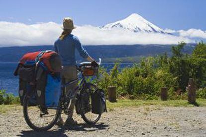 Uma cicloturista contemplando o vulcão Osorno, na região dos Lagos, em Chile.