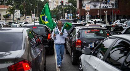 Um vendedor de bandeiras caminha entre os carros em São Paulo.