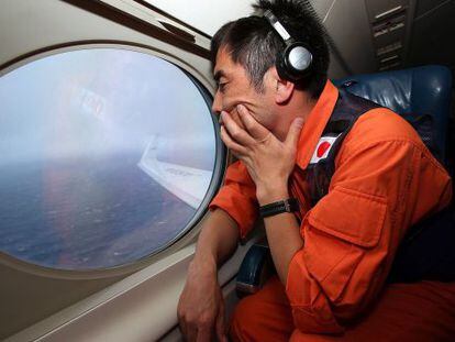Koji Kubota, um salva-vidas japonês, observa o oceano em um Gulfstream V em busca do MH370.