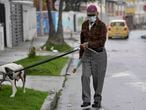 A man wears a face mask as a preventive measure against the spread of the new coronavirus, COVID-19, as he walks his dog in Bogota, on March 16, 2020. - The Colombian government announced the indefinite suspension of face-to-face classes in public schools and universities as a preventive measure against the COVID-19 pandemic. (Photo by Raul ARBOLEDA / AFP)