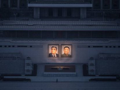 Homem passeia sob os dois grandes retratos de Kim Il-sung (esq.) e Kim Jong-il (dir.) em Pyongyang.