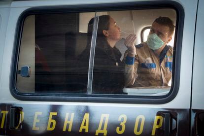 Um funcionário do Serviço Federal Russo de Vigilância coleta amostras para testar o coronavírus na estação de triagem especial ao ar livre no aeroporto de São Petersburgo, em 20 de março.