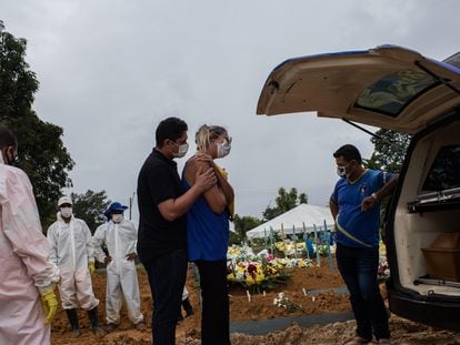 Dois familiares participam do enterro de uma vítima da covid-19 no Cemitério de Nossa Senhora Aparecida em Manaus.