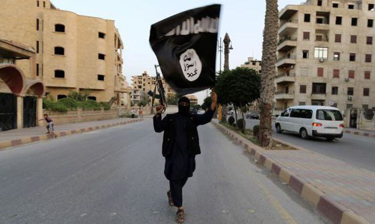 Miliciano com uma bandeira do EI em Raqqa (Síria).