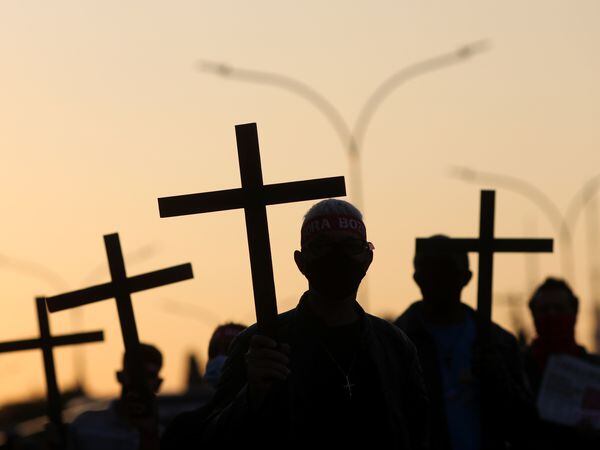 People hold crosses as they attend a tribute to the 100 thousand mortal victims of the coronavirus disease (COVID-19) and a protest against Brazil's President Jair Bolsonaro, in Sao Paulo, Brazil August 7, 2020. REUTERS/Amanda Perobelli