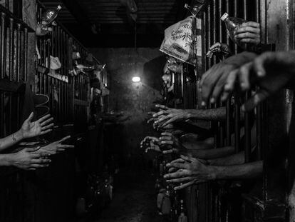 Prisioneiros pedem comida e água em suas celas em uma delegacia de polícia em Caracas.