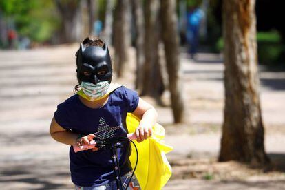 Uma menina protegida com duas máscaras brinca com sua patinete na rua.