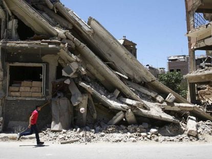Um menino brinca em frente a um edifício destruído em Damasco.