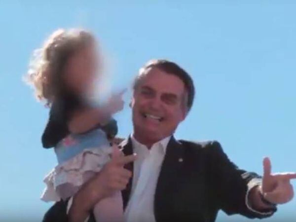 Durante a campanha, Bolsonaro ensina criança a simular arma com a mão.