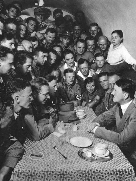 Adolf Hitler, rodeado por correligionários nazistas em uma mesa, em Berlim, em 1933.