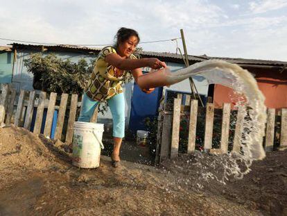 Mulher retira água suja de sua casa em Callao, Peru.