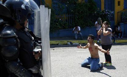 Jovem se ajoelha diante de policiais após morte de colega.