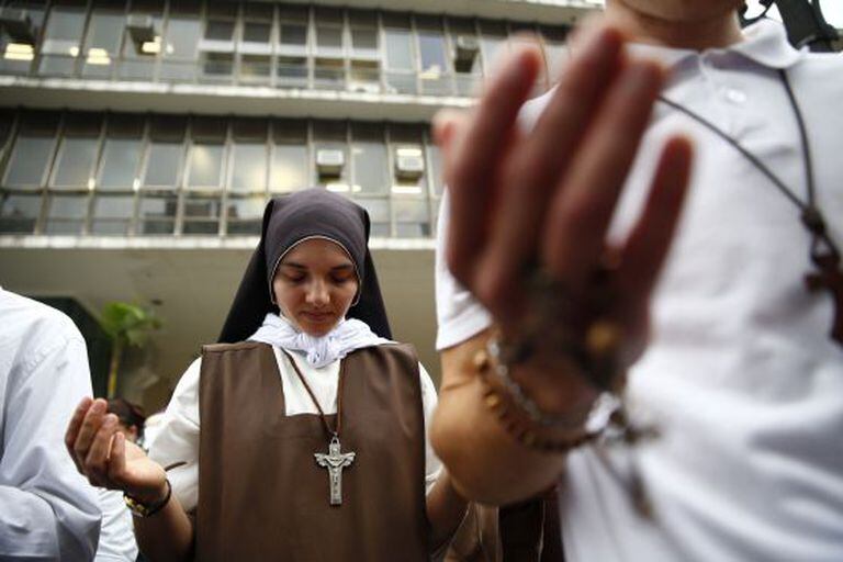 Religiosa reza em frente à Câmara durante votação do plano.