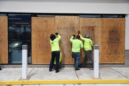Trabalhadores de Miami cobrem as fachadas dos edifícios ante a possível chegada do furacão Dorian.