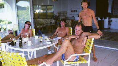 Mark Knopfler, à frente, na ilha de Montserrat (Caribe) com outros membros do Dire Straits, em 1985, o ano em que foi lançada a faixa ‘Money for Nothing’. Em vídeo, atuação de Mark Knopfler em Milão, em 2019, em que troca o “faggot” da letra por “mother”, em alusão a “motherfucker”. / FOTO: GETTY | VÍDEO: FARCO
